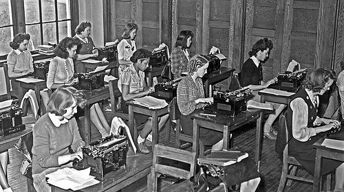 Vintage photograph of girls sitting at desks typing on typewriters