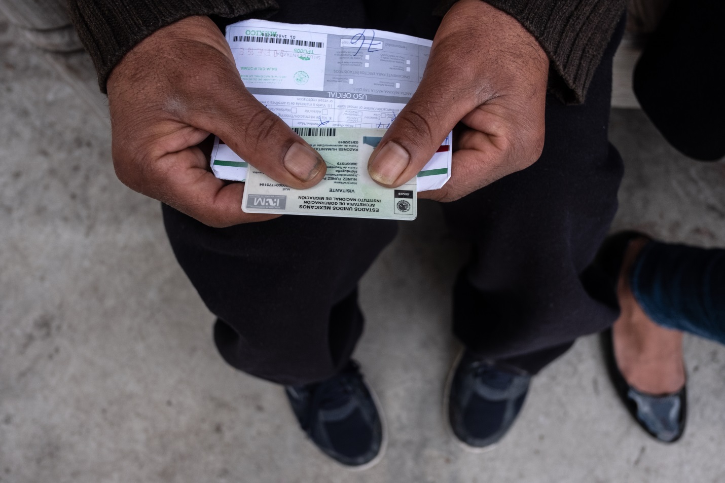 Asylum seeker holds a humanitarian visa card and a piece of paper indicating how long he is legally able to be in Mexico