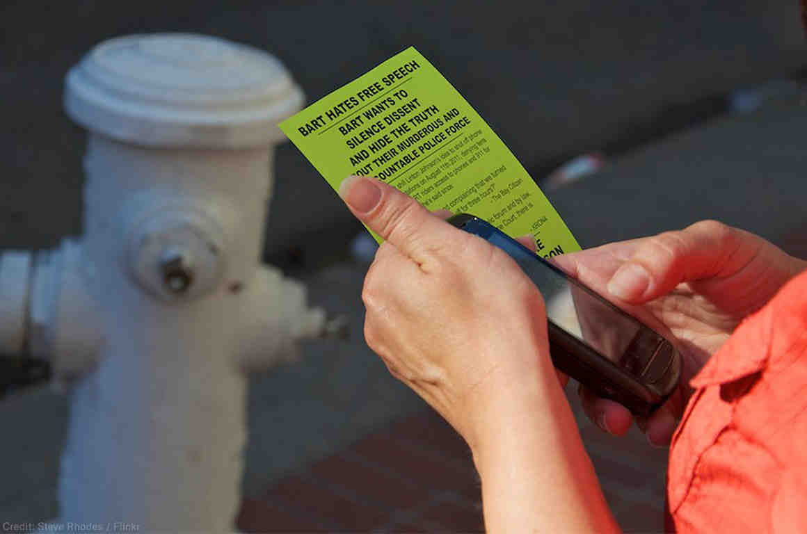 Person holding cell phone and flyer