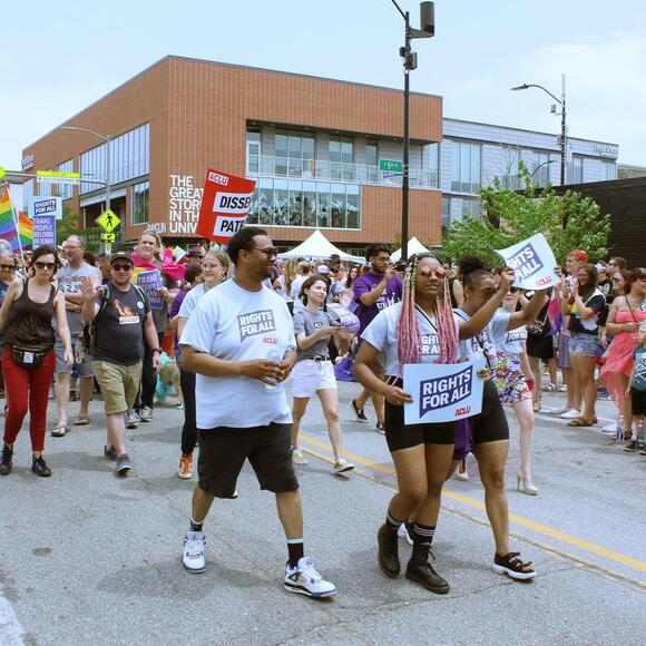 Iowa Pride march. People holding ACLU signs and walking.