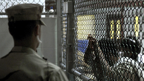 a prisoner is seen through a fence