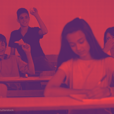 Boys in a classroom throwing paper airplanes at a female student sitting in front of them