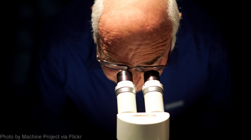 Photo of man peering into microscope