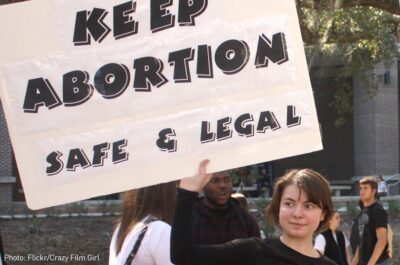 Girl holding "Keep Abortion Safe and Legal" sign