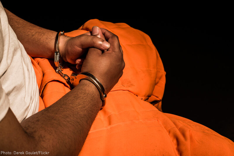 Man with hands cuffed in his lap