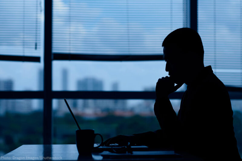 Silhouette of man looking at laptop