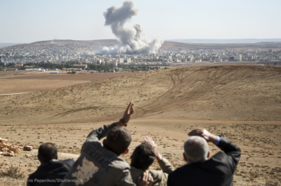 People watching a desert airstrike from a distance