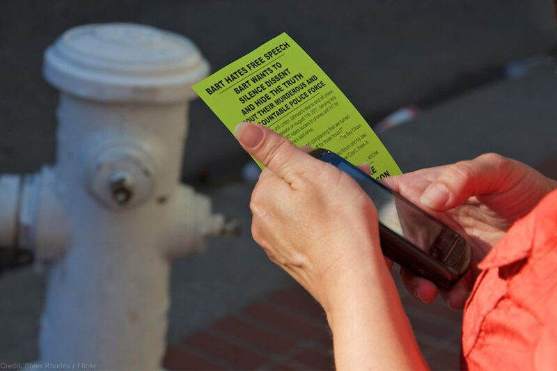 Person holding cell phone and flyer