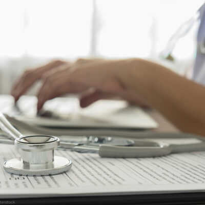 A doctor typing on a laptop computer