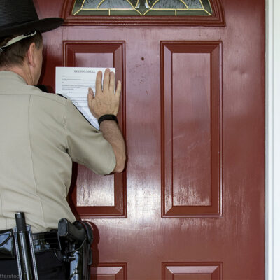 Sheriff placing eviction notice on door