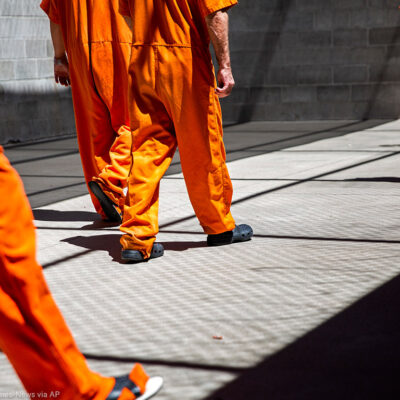 A group of incarcerated people walking a concrete yard