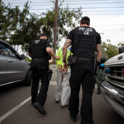 On a sunny day in California, two Immigration and Customs Enforcement (ICE) officers escort a man in handcuffs. Trump administration officials have confirmed plans for two new tactics in their anti-immigrant agenda.