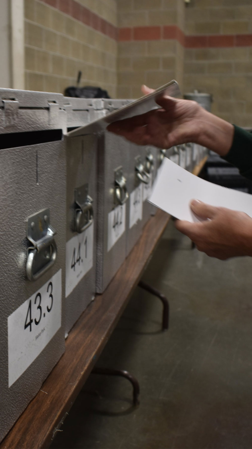 An election worker inserting a ballot into a locked ballot box.