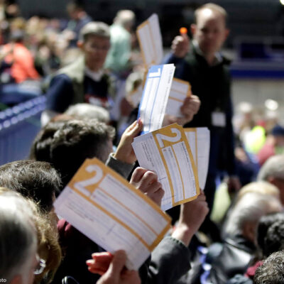 Caucus goers in Des Moines, Iowa hold up their first votes for their 2020 Democratic presidential candidate pick.