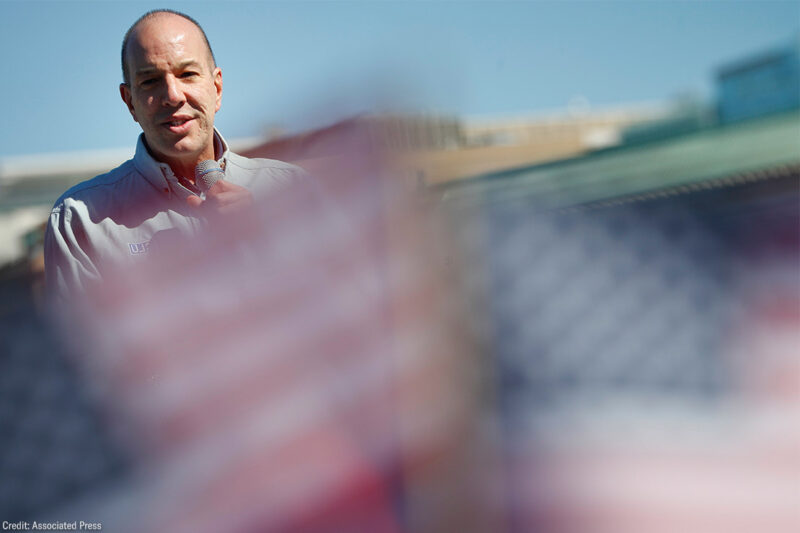 Anthony Romero speaks in the background while mini American flags wave blurred in the foreground.