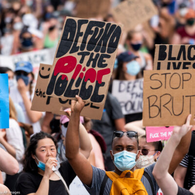 Protestors march down Pennsylvania Avenue holding signs that read “Defund the Police” and “Stop Police Brutality” among other signs.