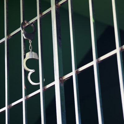 Handcuffs hanging from jail cell.