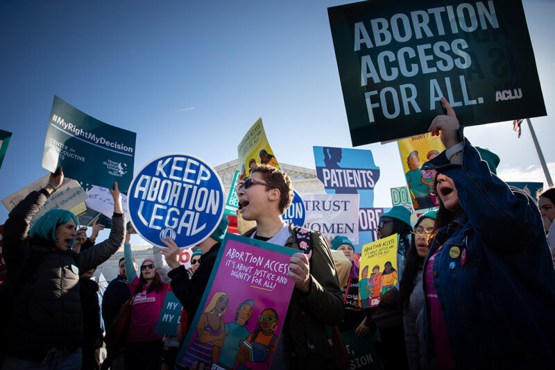 Abortion activists hold signs at rally that read" Keep Abortion Legal" and "Abortion Access for All."