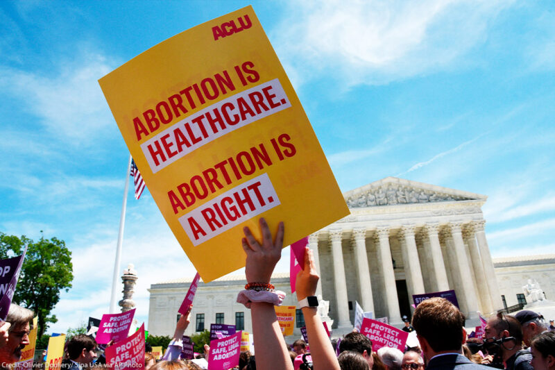 Pro-abortion activist holds ACLU placard that reads "Abortion is healthcare. Abortion is a right." during a rally at the Supreme Court