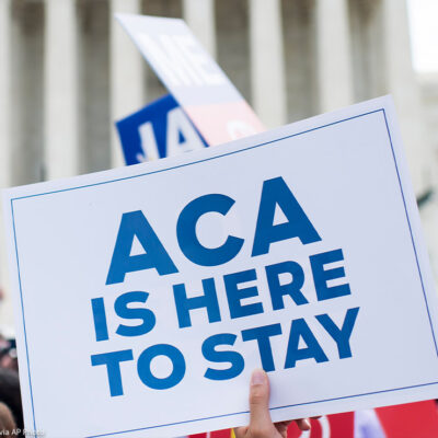 Affordable Care Act Supporter waves sign that reads "ACA is here to stay" outside of the Supreme Court.