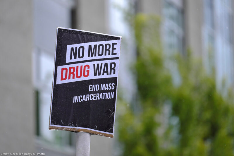 Black and white protest sign reads: "No More Drug War, End Mass Incarceration"