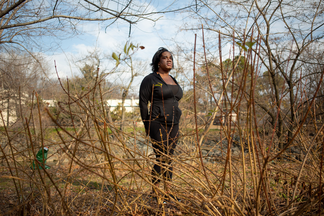 Erica Aries, Black trans woman standing in wooded area.