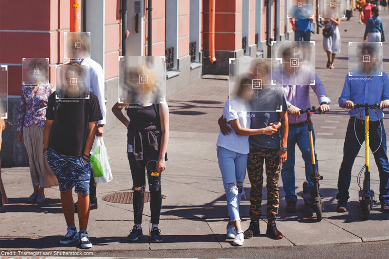 People standing at a crosswalk with face recognition software boxes superimposed over their faces.