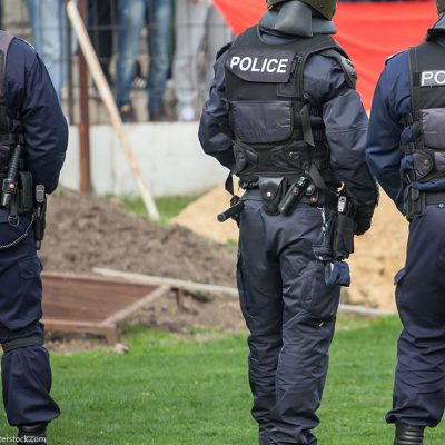 Three police officers in uniform, with "Police" written on the back of their vests.