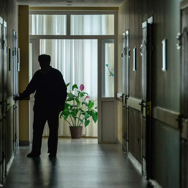 A resident walks down the darkened hall of a nursing home.