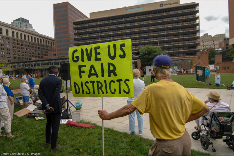 Man holding sign that says, "Give us fair districts."
