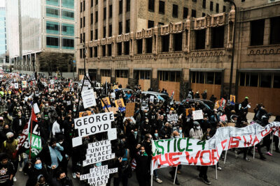 Demonstrators marching and holding signs, protesting the death of George Floyd.