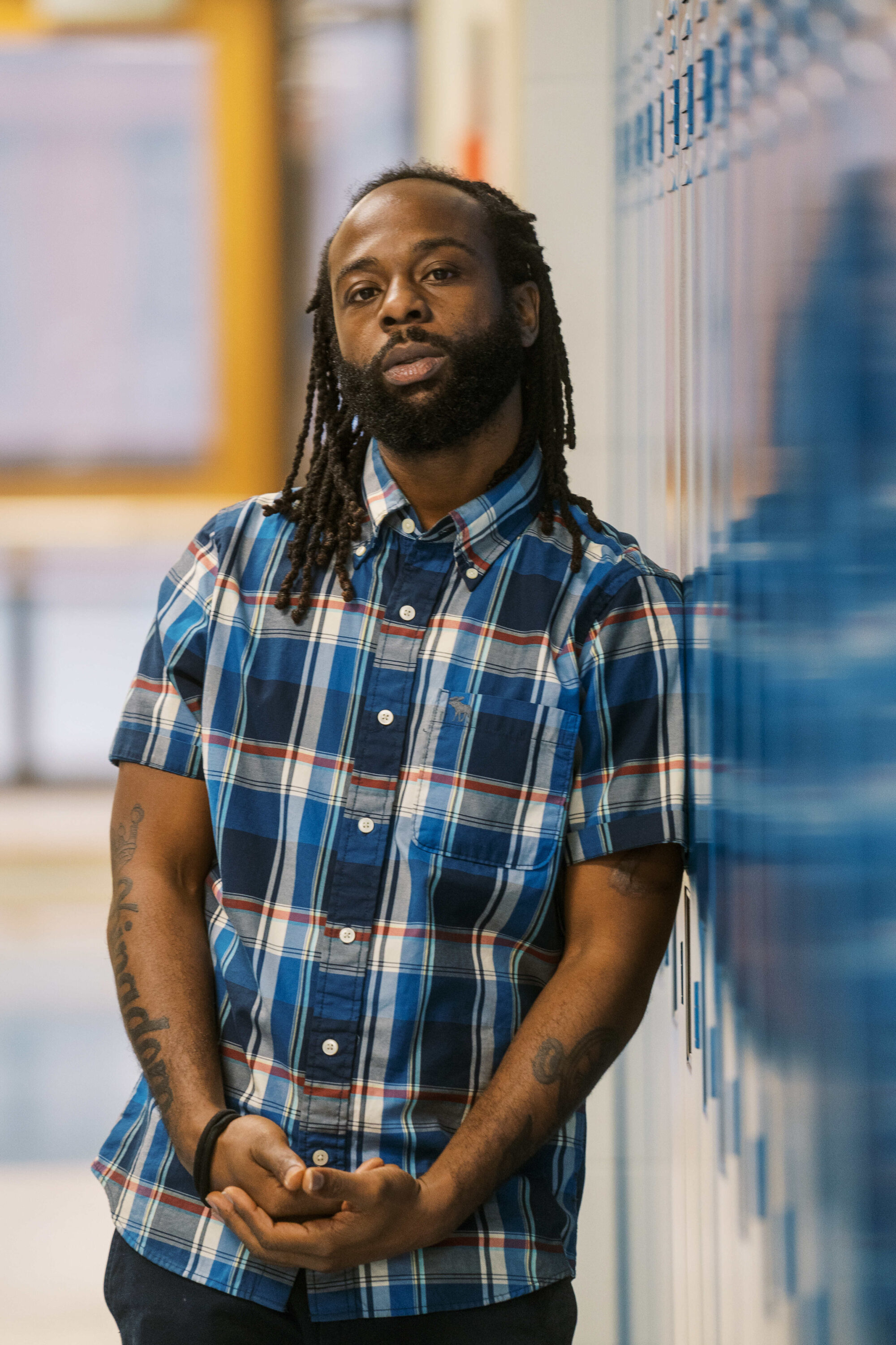 Anthony Crawford, a high school teacher standing in hallway by lockers