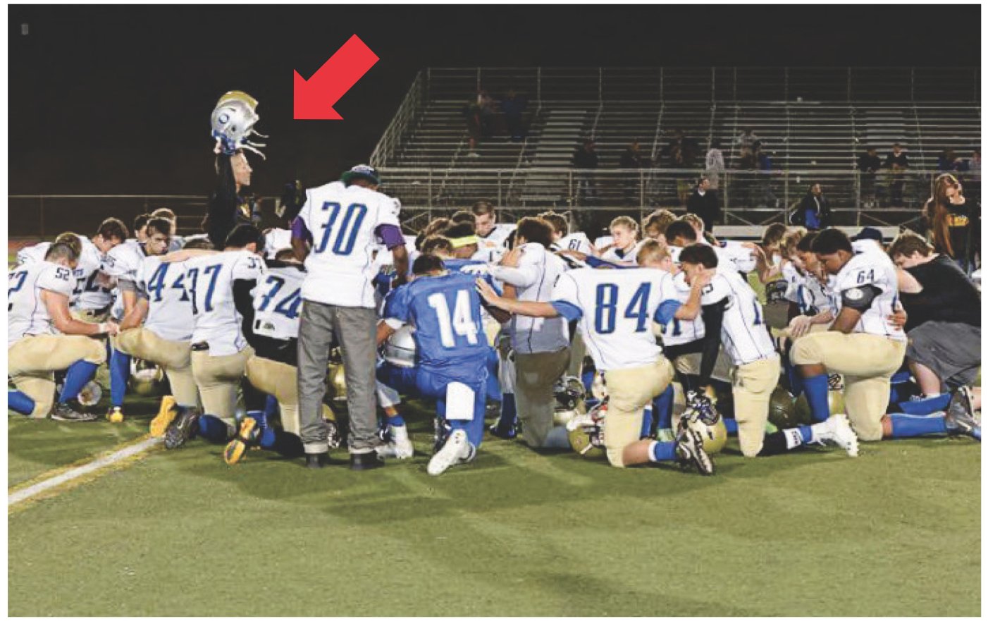 Students being led in prayer by their coach at a Bremerton School District high school. A red arrow is juxtaposed on the image pointing to the coach.