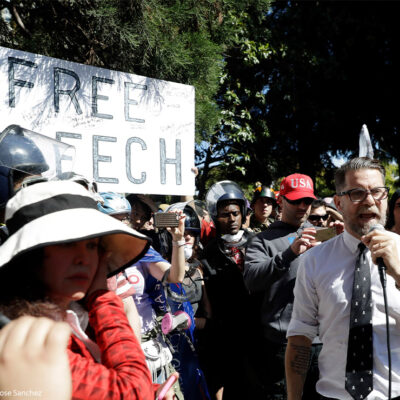 Man speaking to a crowd, rallying for support at a free speech protest.