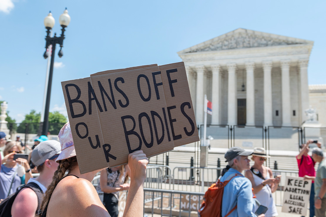 A protester holding a sign reading "BANS OFF OUR BODIES" rallying outside of the Supreme Court.