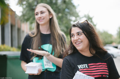 Two smiling canvassers carrying voting information.