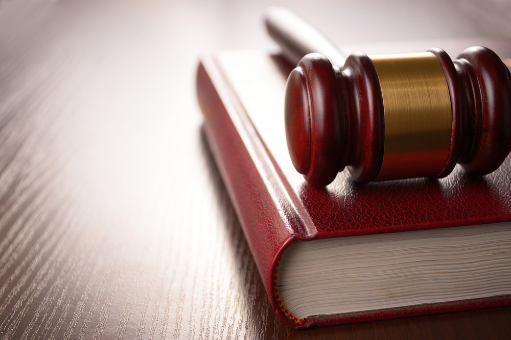 Wooden judges gavel lying on a law book in a courtroom