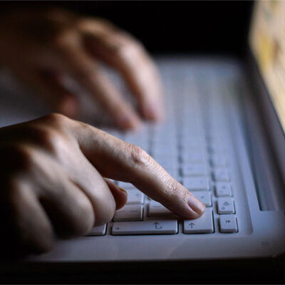 A person using a laptop with just their fingers showing.