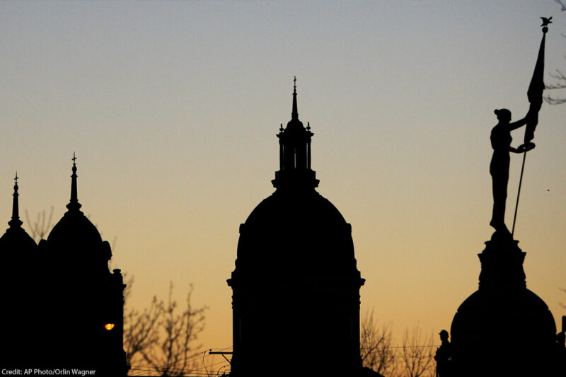 Several buildings and monuments silhouetted against the early morning sky in Wichita, Kansas.