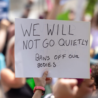 Abortion Rights protestor holds a sign reading "WE WILL NOT GOT QUIETLY, BANS OFF OUR BODIES"