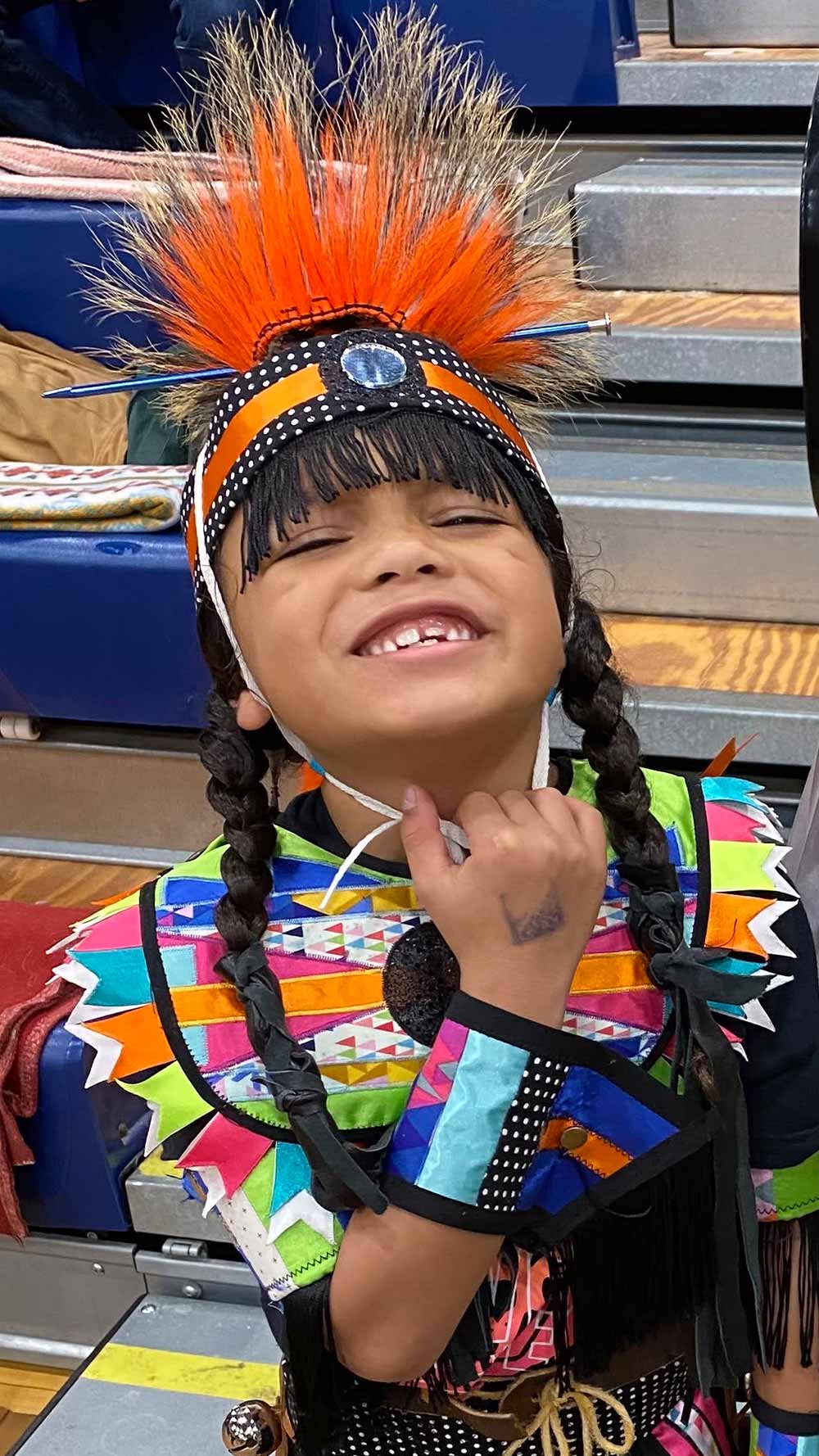 Logan Lomboy in Native American traditional clothing with his hair in braids.