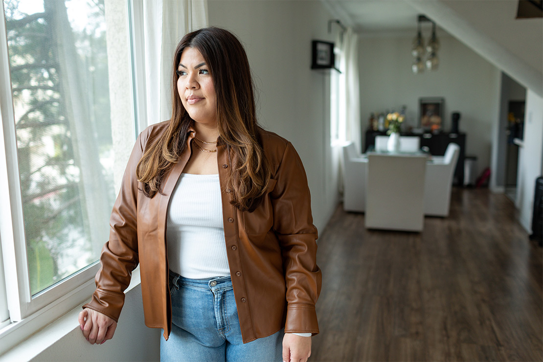 Alyssa Lazo wearily looks from a window from within her home.