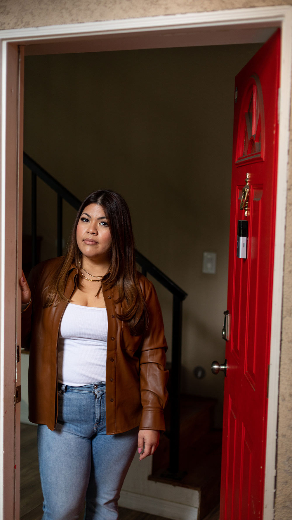 Alyssa Lazo standing by her open red front door.