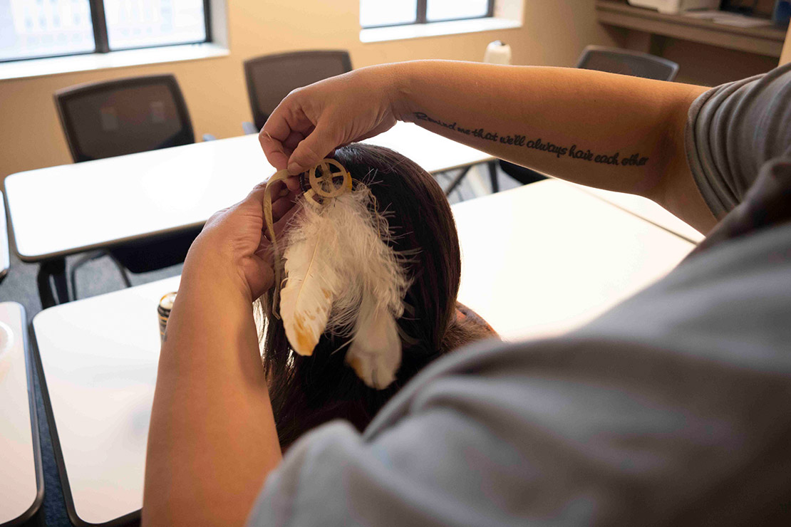 Alice putting a feather in her child's hair.