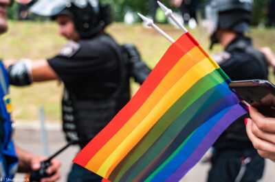 LGBTQ flag with police in the background.