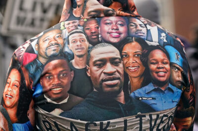 An individual with a sweatshirt featuring faces of the many victims of police violence.