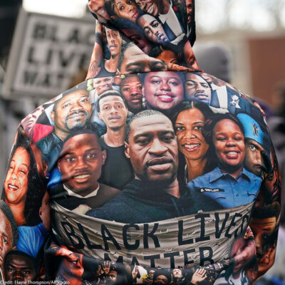 An individual with a sweatshirt featuring faces of the many victims of police violence.