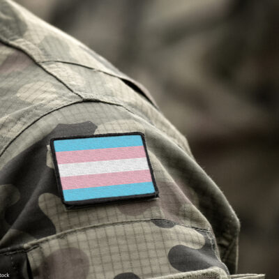 Transgender Pride flag on shoulder of a military camouflage uniform.