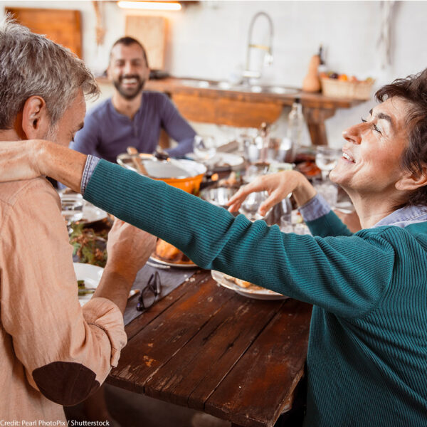 Group of diverse people together around food at dinning table, talking and gathering for Holiday