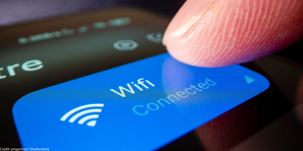 A finger touching a phonescreen to connect to wifi.